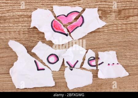 Zerrissenes Papier mit Worten Liebe Nahaufnahme auf Holztisch Stockfoto