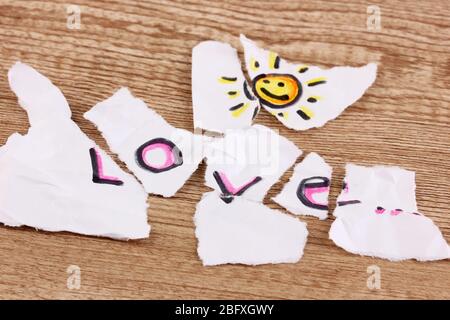 Zerrissenes Papier mit Worten Liebe Nahaufnahme auf Holztisch Stockfoto