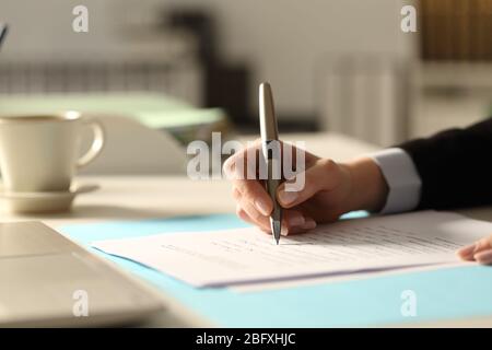 Nahaufnahme der Geschäftsfrau Hände Ausfüllen Formular in der Nacht im Büro Stockfoto