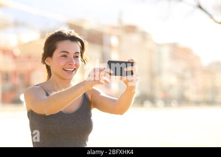 Glückliche Frau, die Selfie mit Smartphone nimmt, lächelt auf der Straße Stockfoto