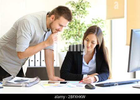 Zwei Führungskräfte, die sich grafische Berichte anguten, arbeiten an einem Schreibtisch im Büro Stockfoto