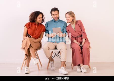 Schöner Mann in blauem Hemd mit digitalen Tablet während der Anzeige Bild im Internet an Freunde Stockfoto