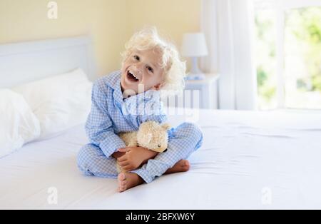 Bleib zu Hause. Kinder spielen im Bett während der Quarantäne und Sperrung. Kind im sonnigen Schlafzimmer. Kleiner Junge in blauem Schlafanzug. Schlafbekleidung und Bettwäsche für Kinder und Stockfoto