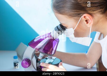 Ein Mädchen untersucht einen Flügel einer Fliege unter dem Mikroskop Stockfoto