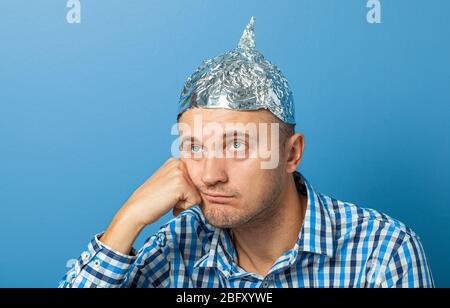 Folienhut auf Mann. Mann mit einem gelangweilten Gesicht. Schützt vor dem Lesen denken. Stockfoto