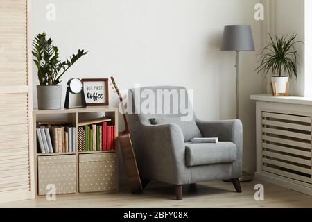 Hintergrundbild von gemütlichen Leseecke in modernen minimalistischen Innenraum, Fokus auf grauen Sessel gegen weiße Wand, kopieren Raum Stockfoto
