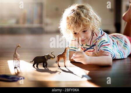 Kind Schatten Zeichnung Tiere. Kinder spielen zu Hause. Fun Basteln für Kindergartenkinder. Kleiner Junge, der Giraffe und Elefanten in einem sonnigen Schlafzimmer malt. Spiel Stockfoto