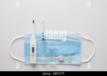 Medizinische Maske auf blauem, blauem Hintergrund.Gesichtsmaske. Maske für Krankheiten. Thermometer und Medikation. Einweg-Gesichtsbild. Medizinischer Atemverband Gesicht. Konzept der Quarantäne von Coronavirus. Stockfoto