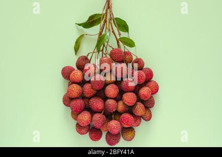 Frische Litschi Früchte mit Blättern auf grünem Hintergrund. Hintergrundkonzept Draufsicht. Stockfoto