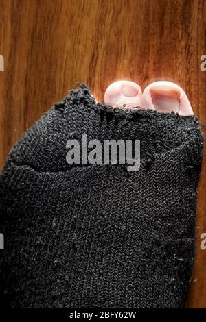 mans Zehen stocken aus dem Loch in schwarzen Socken Stockfoto