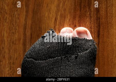 mans Zehen stocken aus dem Loch in schwarzen Socken Stockfoto