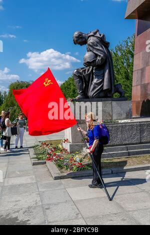 9. Mai 2016, Berlin, am Sowjetischen Kriegsdenkmal im Treptower Park, einem Denkmal und zugleich einem Militärfriedhof, erinnern zahlreiche Russen und Deutsch-Russen mit vielen bunten Fahnen an den 71. Siegestag am Ende des Zweiten Weltkriegs. Das Denkmal wurde 1949 in Deutschland auf Anweisung der sowjetischen Militärverwaltung errichtet, um die Soldaten der Roten Armee zu ehren, die im Zweiten Weltkrieg starben Über 7000 der in den Berliner Schlaghs verstorbenen Soldaten sind hier begraben. Blume auf dem knienden Soldaten. Weltweit verwendet Stockfoto