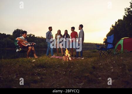 Eine Gruppe von Menschen durch die Lagerfeuer sitzen neben dem Zelt in der Nacht im Sommer in den Herbst. Stockfoto