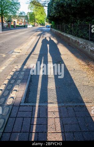 Northampton, Großbritannien. April 2020. Lange Schatten werfen entlang der Bürgersteig auf einer ziemlich Billing Straße, die in die Stadt von der frühen Morgensonne als ein Paar ihre Stunden Sport, (Morgen zu Fuß), bevor viele Menschen auf den Straßen, Northampton. Kredit: Keith J Smith/Alamy Live News Stockfoto