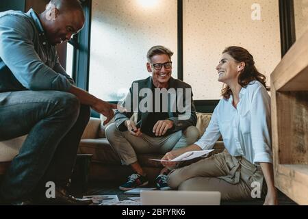 Gruppe von Geschäftsleuten, die ein Meeting abhalten. Diverse Gruppe von Designern lächelt während eines Meetings im Büro. Stockfoto