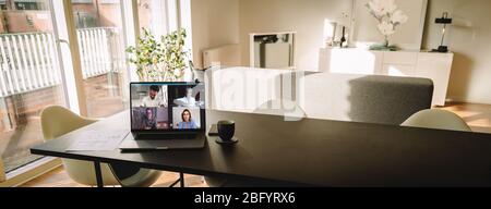 Laptop auf dem Tisch mit einem Videoanruf auf dem Bildschirm im Wohnzimmer. Menschen, die VoIP nutzen, um sich miteinander zu verbinden. Stockfoto