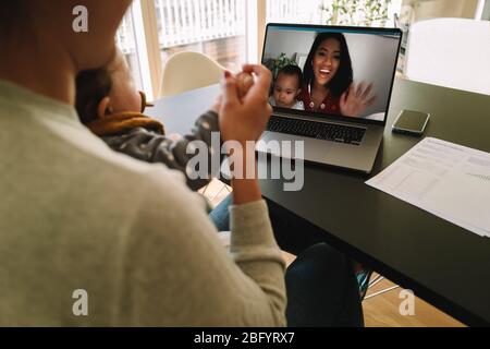 Frau, die während der Quarantäne einen Laptop benutzt, um sich mit ihrer Schwester zu verbinden. Freundinnen mit ihren Kindern, die zu Hause einen Videoanruf auf einem Laptop-Computer führen. Stockfoto