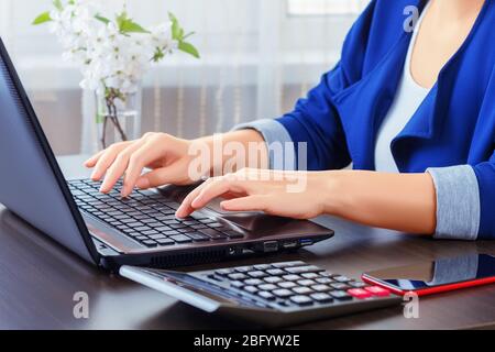 Nahaufnahme der Hände einer Buchhalterin, die auf einem Laptop tippt, während sie von einem Home Office aus arbeitet. Stockfoto