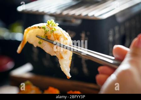 Aburi Engawa Sushi (Fluke fin), Gourmet Meeresfrüchte wird mit Metall Essstäbchen geklemmt. Buffet Mit Japanischer Küche. Stockfoto