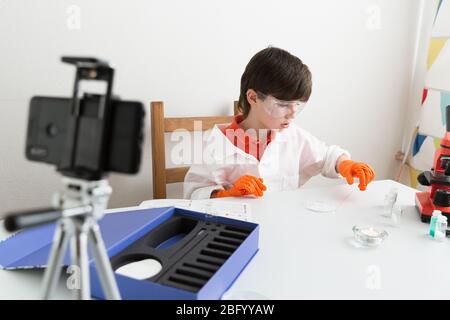 9-jähriger Junge macht pädagogisches Video über chemische Experimente Für seinen Vlog Stockfoto