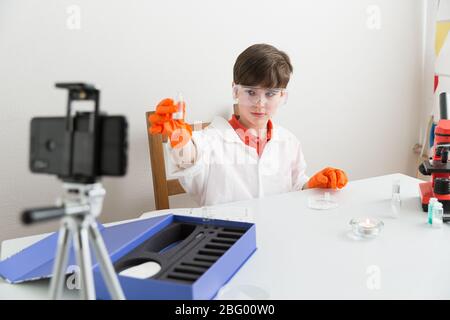 9-jähriger Junge macht pädagogisches Video über chemische Experimente Für seinen Vlog Stockfoto