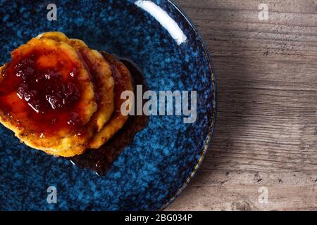 Pfannkuchen mit Erdbeermarmelade. Stilvolles Frühstück, schöner Teller auf einem Holztisch. Hausgemachte Speisen, einfaches Rezept. Ein gesundes Leben. Flaches Lay. Luxus Stockfoto