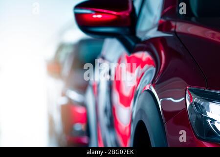Nahaufnahme Scheinwerfer des roten Autos in modernen Showroom geparkt. Neues und luxuriöses Auto. Konzept des Autohauses. Automobilindustrie. Kfz-Leasing. Vorderansicht Stockfoto