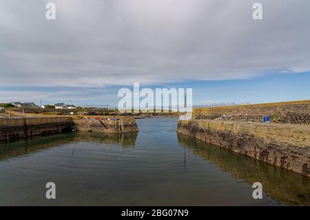 Der Eingang zum Binnenhafen am Hafen von Slade bei Ebbe an einem hellen Oktobernachmittag mit seinen mit Hummer- und Krabbentöpfen beladenen Quays. Stockfoto