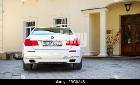 Grodno, Weißrussland, 16. Mai 2013: Moderner Luxus BMW 750Li XDrive Auto hinten zurück Blick auf Stein geparkt gepflasterte Parkplätze in der Nähe von Ancient House horizontal. Stockfoto