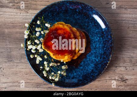 Frühstück, Essen. Pfannkuchen mit Erdbeermarmelade auf einem blauen Teller mit Blumen. Mittagessen, Snack. Familienessen. Hausmannskost. Flaches Lay. Stockfoto