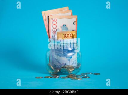 In einem Glasgefäß. Kasachstan, KZ, KZT. Banknote, Papierwährung, Münzen, Bank. Gehalt, Kredit, Einsparungen, Bezahlung und Ausgaben. Wirtschaft und Wirtschaft.