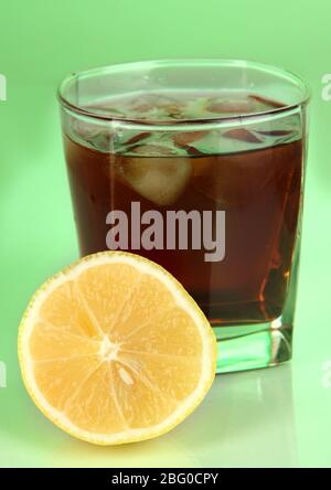 Glas Whisky mit Eis und Zitrone auf grünem Hintergrund Stockfoto