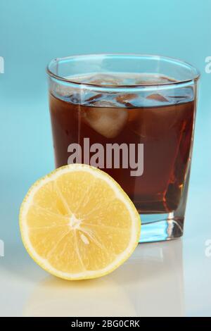 Glas Whisky mit Eis und Zitrone auf blauem Hintergrund Stockfoto