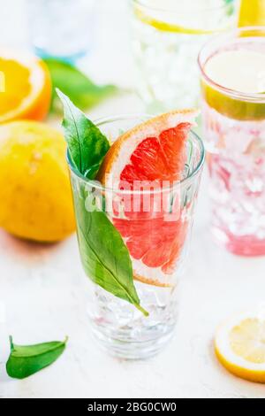 Sommer erfrischendes Getränk mit Grapefruit Scheiben und grünen Blättern im Sonnenlicht auf weißem Tisch , Nahaufnahme. Infundiert Detox Wasser. Vitamin C. Antioxidans Stockfoto