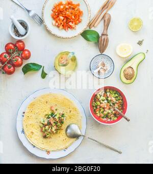 Tortilla wickelt Sandwiches Vorbereitung mit leckeren frischen Avocado Tomaten Salsa Salat auf weißen Küchentisch Hintergrund, Draufsicht. Gesunde Ernährung. Vegetari Stockfoto