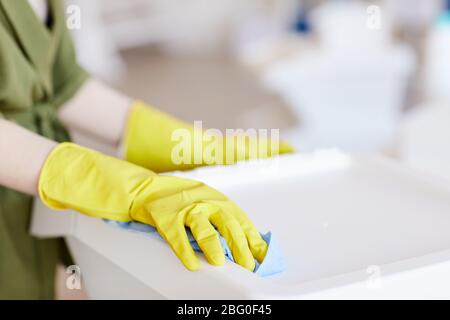 Nahaufnahme einer nicht erkennbaren Frau, die gelbe Gummihandschuhe trägt, während sie zu Hause Plastikbehälter reinigt, kopieren Sie den Raum Stockfoto