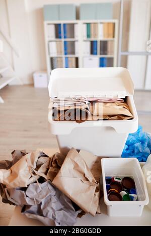 Vertikales Hintergrundbild verschiedener Abfallteile sortiert nach Materialart und bereit für das Recycling im Büroinnenraum, Schwerpunkt Papierbehälter im Vordergrund, Stockfoto
