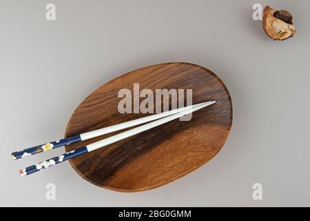 Minimalistische Szene aus leeren Holzschüssel und Essstäbchen, heller Hintergrund Stockfoto
