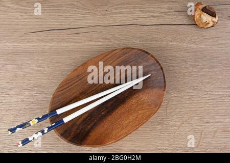 Minimalistische Szene aus leeren Holzschüssel und Essstäbchen, heller Holzhintergrund Stockfoto