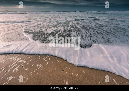 Eine sich zurückziehende Ebbe an einem kalten kühlen Abend am Fistral Beach in Newquay in Cornwall. Stockfoto