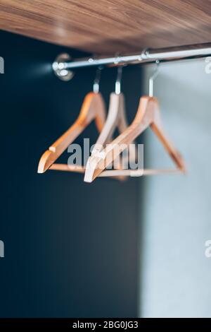 Leere Holzaufhängungen auf der Schiene im schrank. Lifestyle-Komposition mit natürlichem Licht und Kopierraum Stockfoto