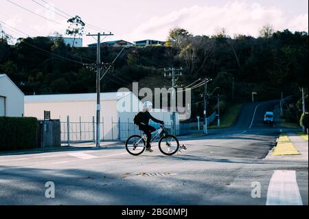19/4/2020 Asiatin mit einem Fahrrad fahren mit einem Hund im Herbst im Botanischen Garten, Oamaru, Neuseeland. Konzept über Bewegung während soziale Isolatio Stockfoto