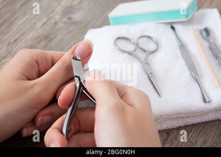 Eine Frau macht eine Maniküre zu Hause. Maniküre-Werkzeuge. Maniküre mit Kanten. Schnitt, Wunde am Finger, Blut. Gefährliche Maniküre. Häusliche Pflege, Spa, Schönheit. Stockfoto