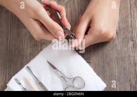 Eine Frau macht eine Maniküre zu Hause. Maniküre-Werkzeuge. Maniküre mit Kanten. Schnitt, Wunde am Finger, Blut. Gefährliche Maniküre. Häusliche Pflege, Spa, Schönheit. Stockfoto