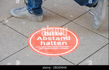 Hannover, Deutschland. April 2020. Ein Schild "Bitte halten Sie Abstand" ist auf dem Boden vor dem Eingang eines Geschäfts geklebt. Nach mehrwöchigen Schließungen während der Corona-Pandemie haben heute wieder die ersten Geschäfte in Niedersachsen eröffnet. Kredit: Julian Stratenschulte/dpa/Alamy Live News Stockfoto