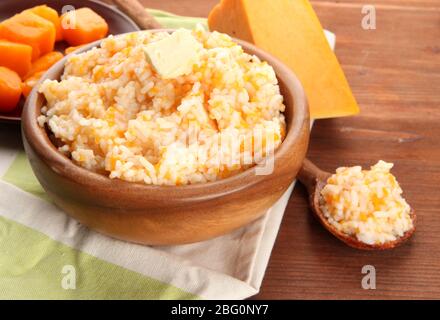 Schmecken Sie Reis Brei mit Kürbis in Schüssel auf Holzhintergrund Stockfoto