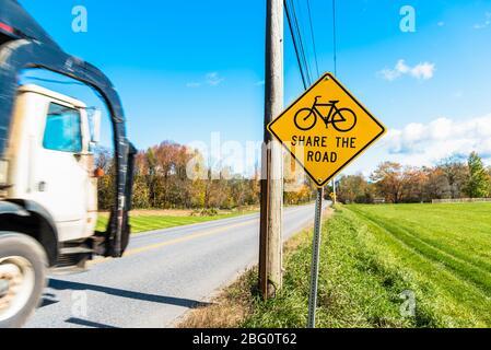 Verkehrsschild warnt Fahrer vor Fahrrädern auf einer belebten Landstraße an einem sonnigen Herbstmorgen Stockfoto