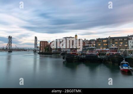 Blick auf die Skyline von Portsmouth und die Liftbrücke bei Sonnenuntergang. Schlepper Boote sind im Vordergrund sichtbar. Lange Belichtung. Stockfoto