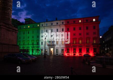 Rom, Italien - 8. April 2020: Palazzo Chigi, Sitz der italienischen Regierung, Fassade des Gebäudes mit den Farben der italienischen Flagge d beleuchtet Stockfoto