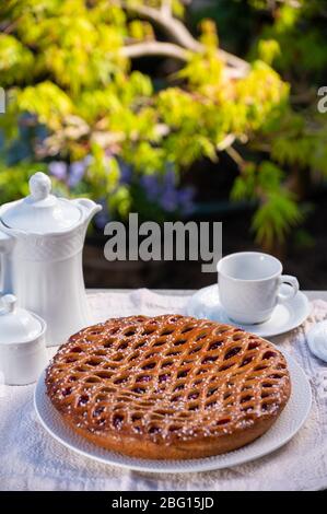 Kirschkuchen mit Teiggitter aus Limburg, Niederlande serviert in sonnigen Garten Stockfoto
